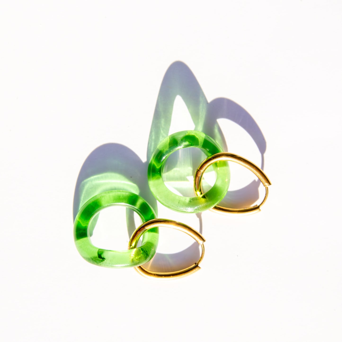 Pair of green and gold hoop earrings on a white background