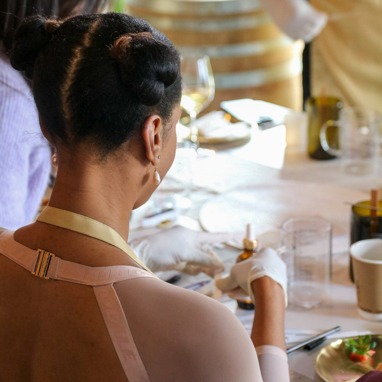 Two women sitting at a table making candles with a blurred background