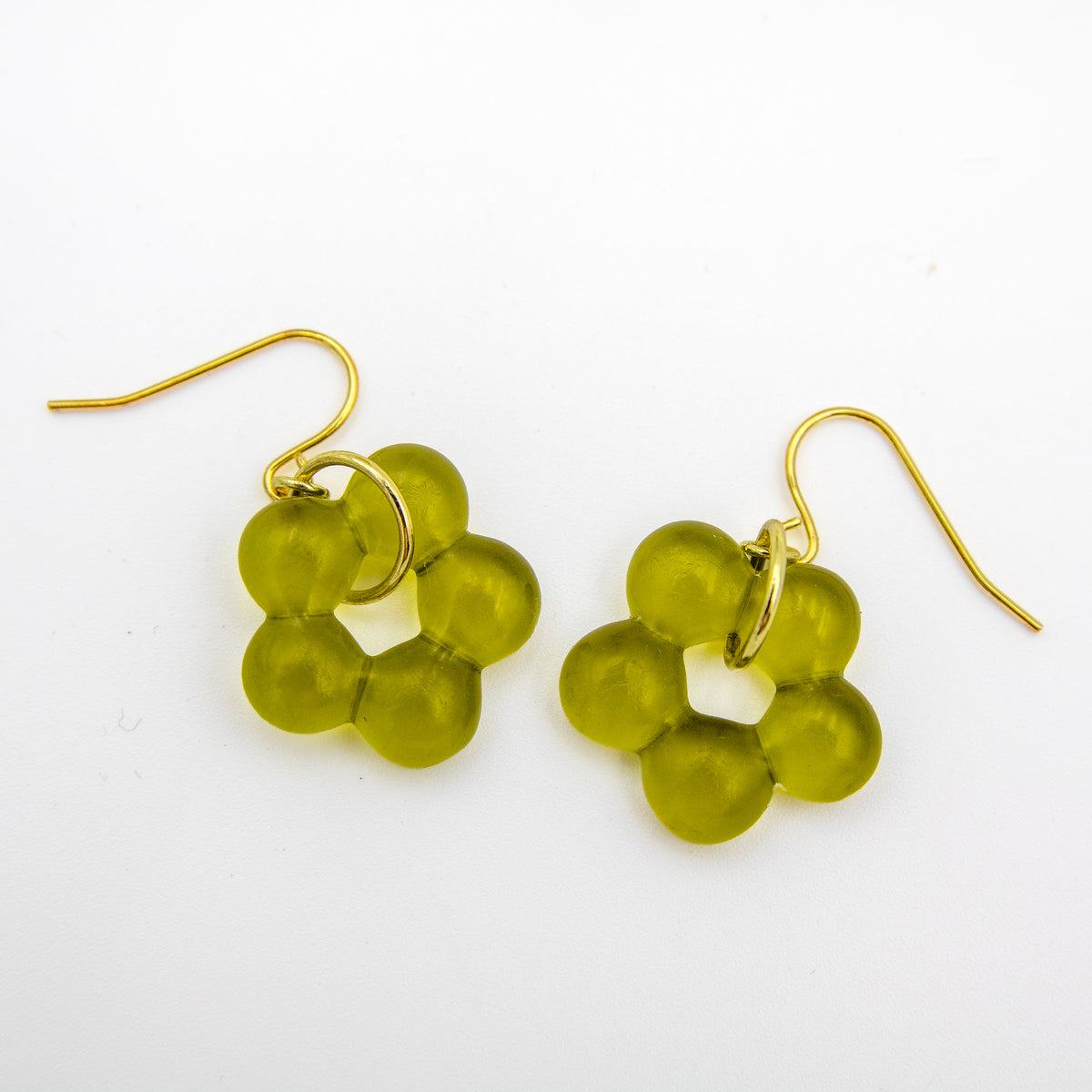 A pair of gold-tone dangle earrings with translucent olive green flower-shaped beads, displayed on a clean white background.