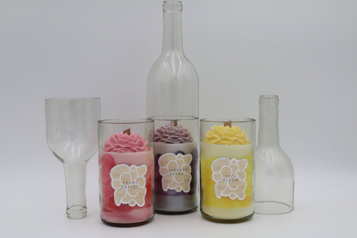 Decorative candles in glass containers with floral designs on a white background