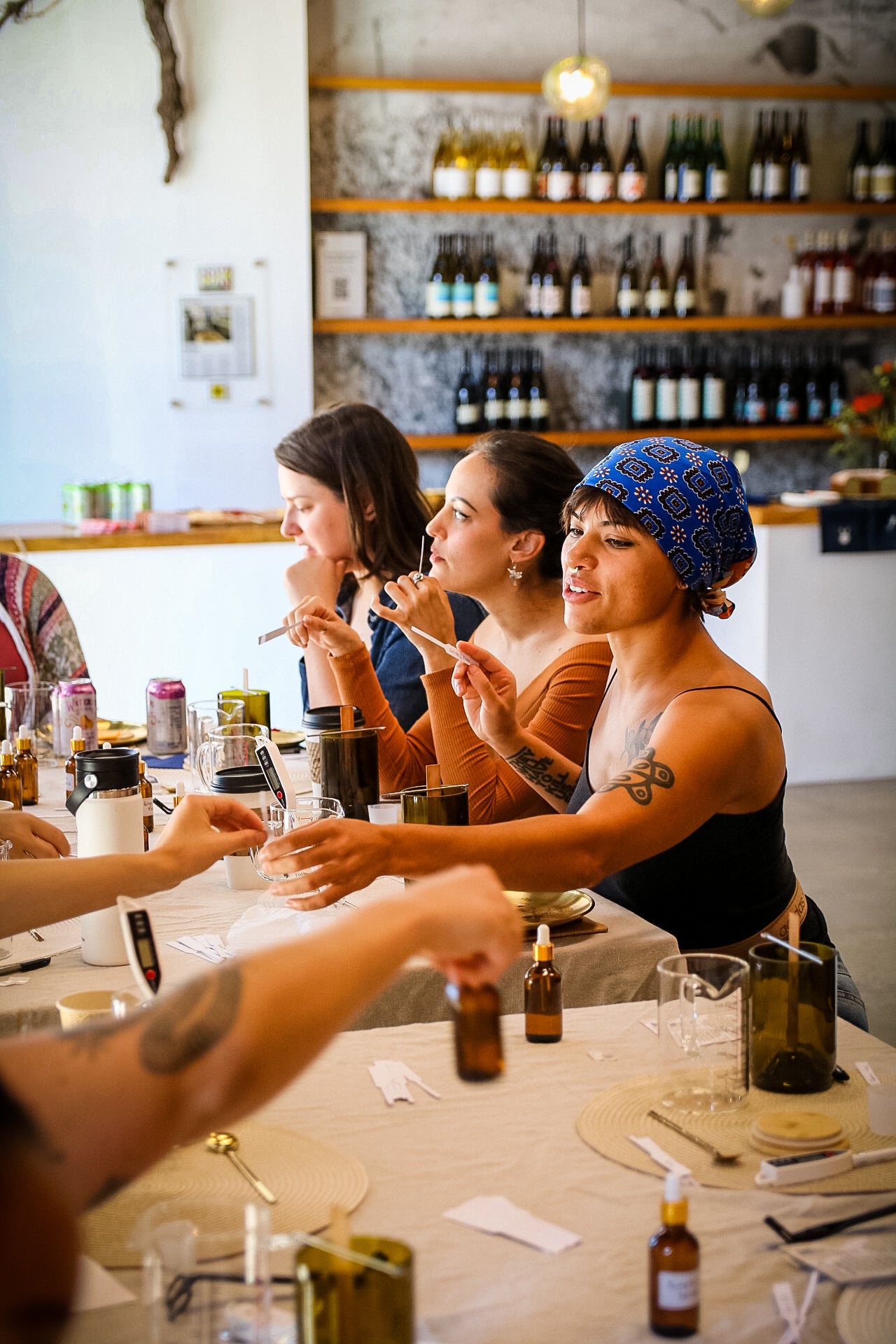 Group of women enjoying drinks and candle-making together at a bar or restaurant.