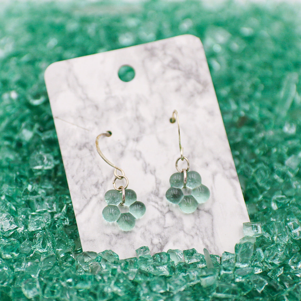 Blue automotice glass earrings on a marble card with blue shattered glass  in the background
