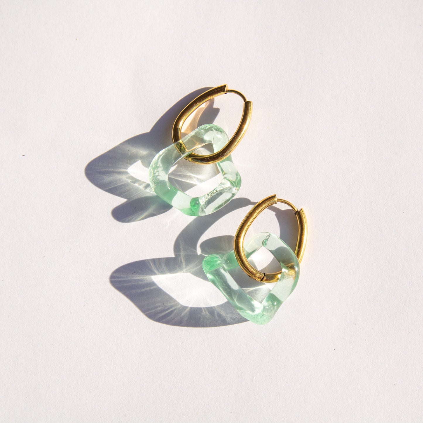 Gold and seafoam glass hoop earrings on a white background