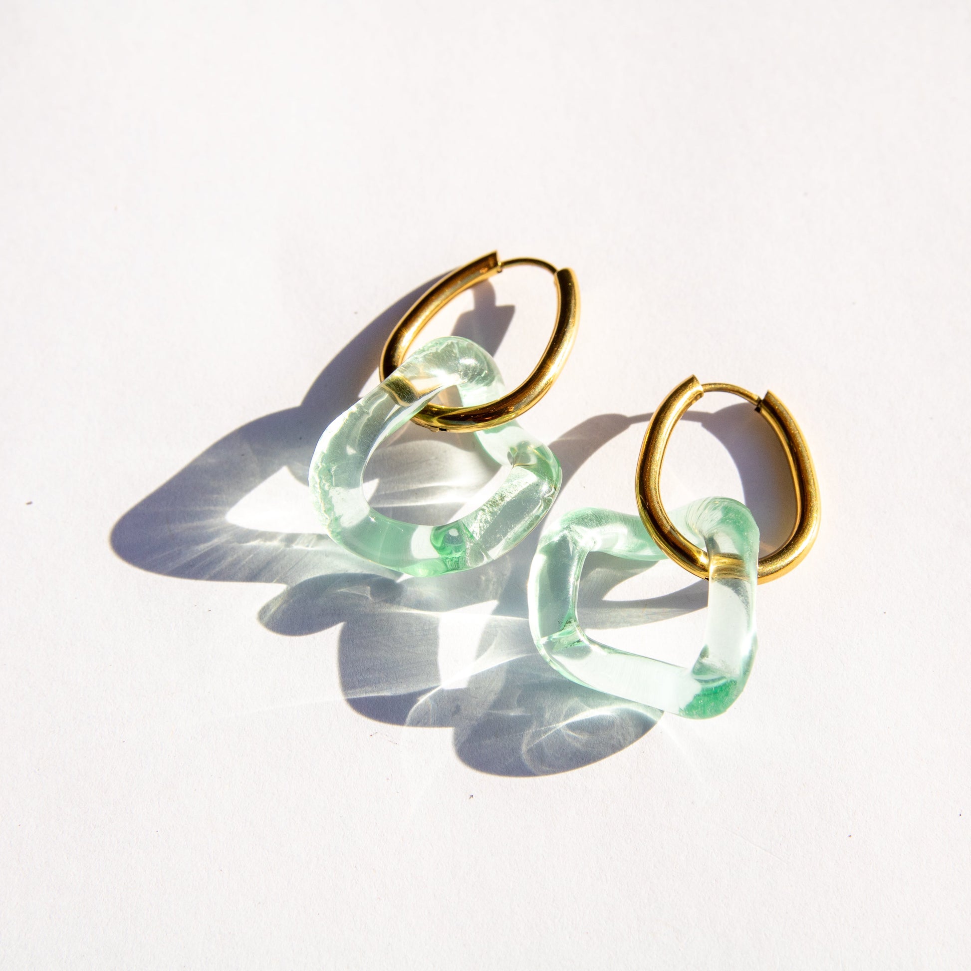 Gold hoop earrings with seafoam translucent circular hoops on a white background