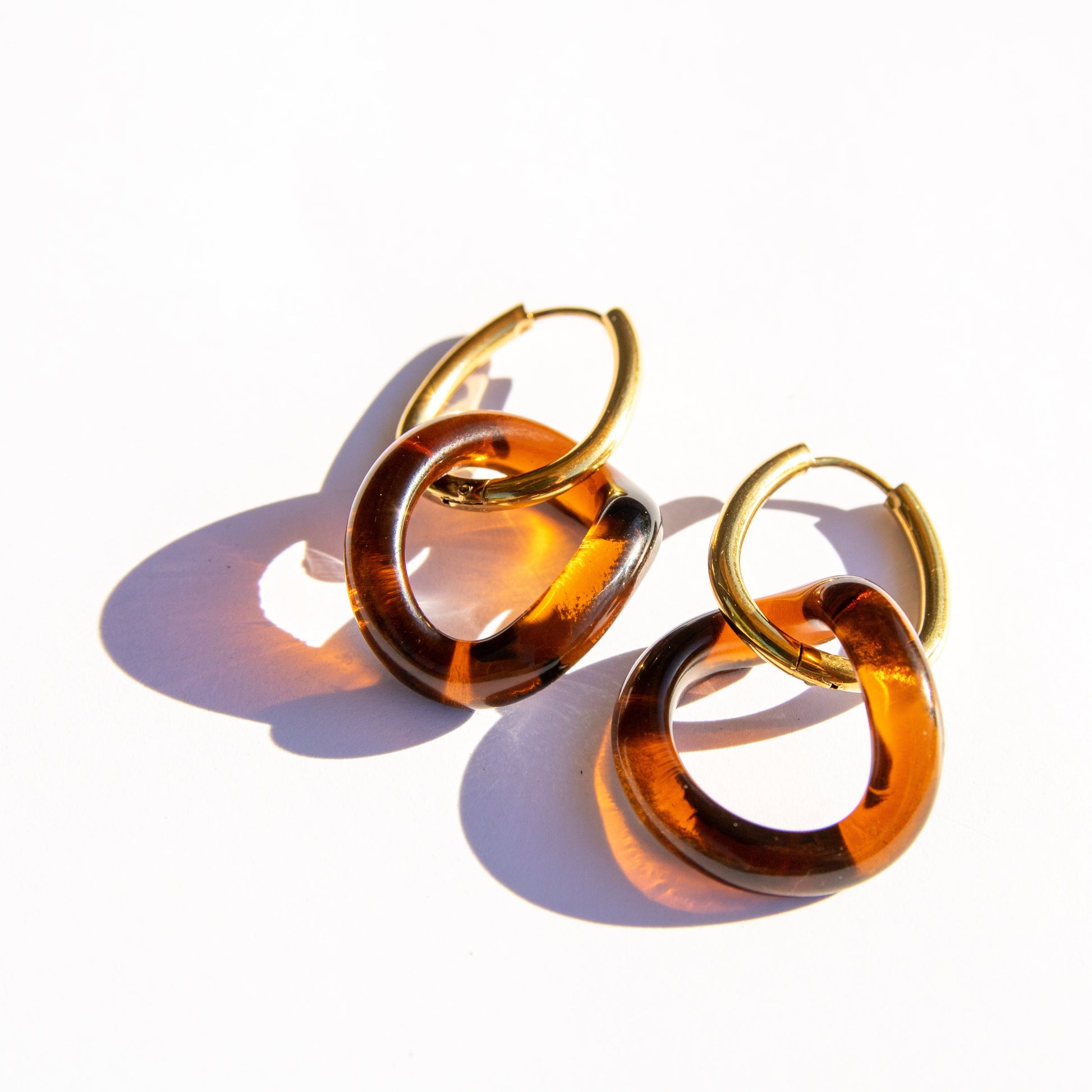 Pair of amber hoop earrings on a white background